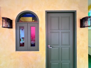 A door with a window above it, both with a simple design, and a wall-mounted light fixture to the left. - The Snug Airportel (Sa Khu)