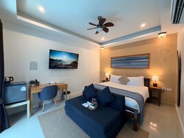 Una habitación de hotel moderna con cama, escritorio, silla y ventilador de techo.