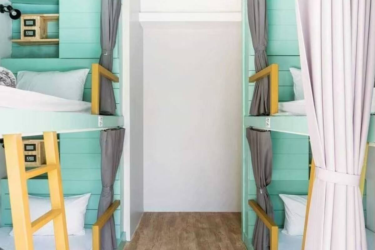 Een kamer met stapelbedden, een trapje en een garderobe.