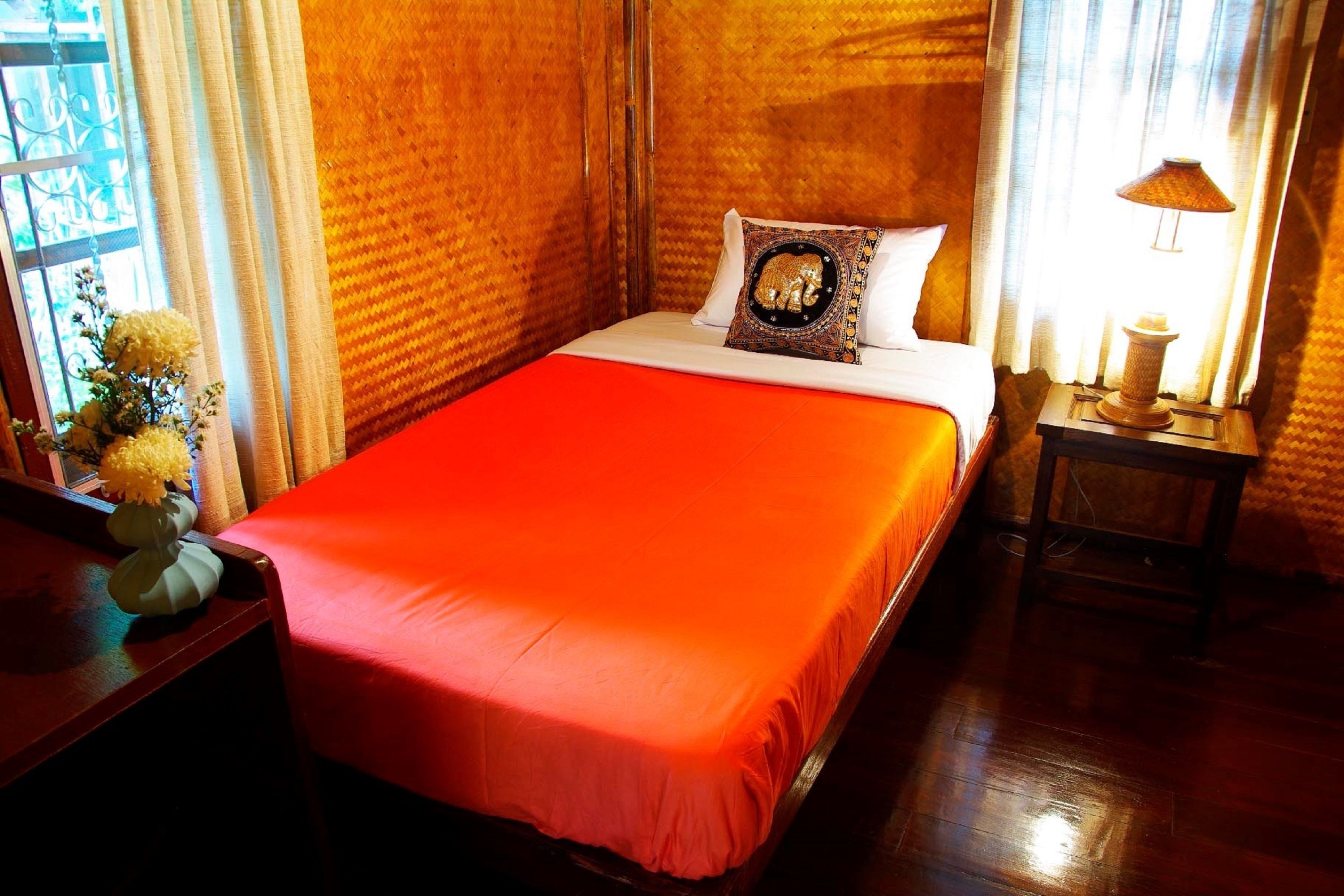 A hotel room with a large bed, a nightstand with a lamp, and a vase with flowers on the left side.