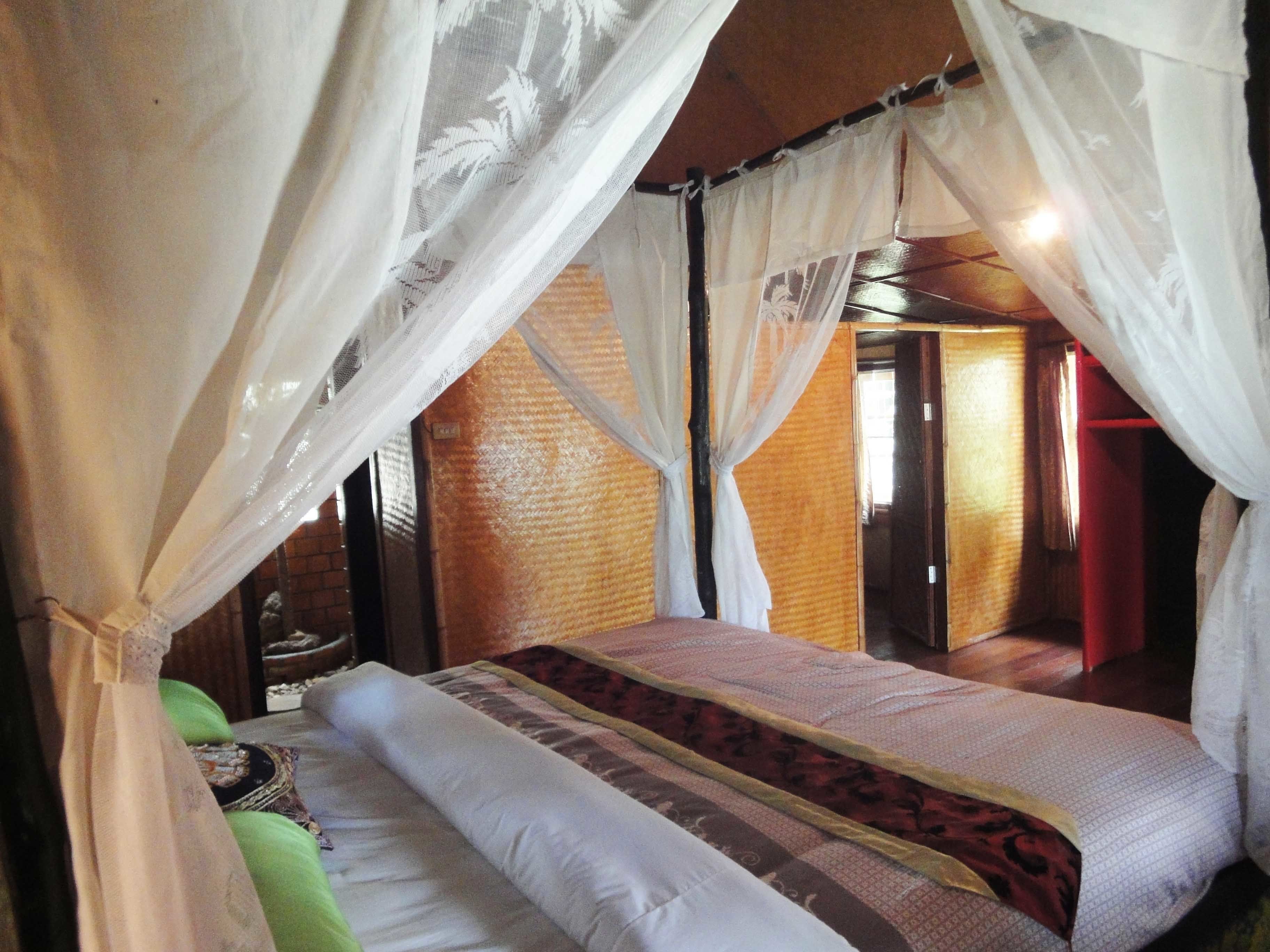 A room with a bed, a nightstand, and a window with curtains.