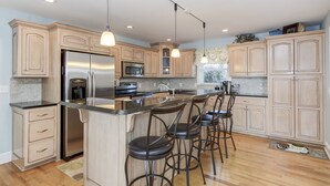 A modern kitchen with a central island, stainless steel appliances, and bar stools. - #1 Rated Vacation Home w/ Deep Water on the Main Channel (Taylorsville)