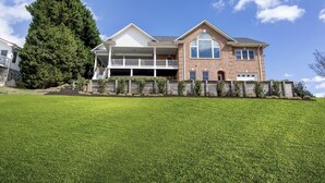 A two-story house with a covered porch, a garage, and a large lawn. - #1 Rated Vacation Home w/ Deep Water on the Main Channel (Taylorsville)