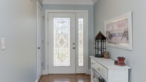 A hallway with wooden flooring, white walls, and a white console table with a framed picture and a lantern. - #1 Rated Vacation Home w/ Deep Water on the Main Channel (Taylorsville)