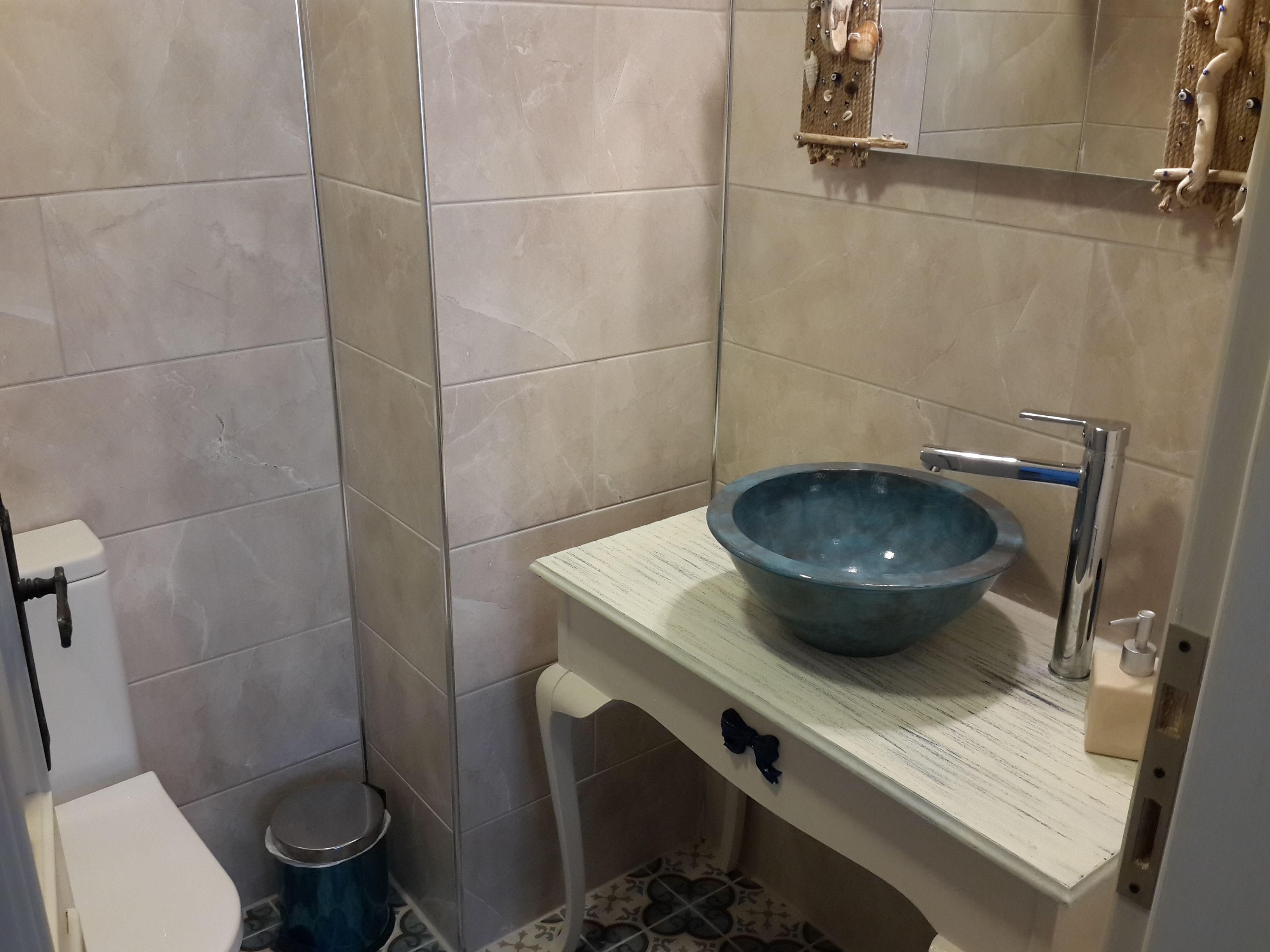 Une salle de bain avec un lavabo blanc, un bac bleu, des toilettes blanches et une poubelle.