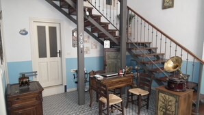 A room with a wooden desk, two chairs, a bookshelf, a gramophone, a staircase with a metal railing, and a door with a frosted glass panel. - Gizemli Konak (Ayvalik)