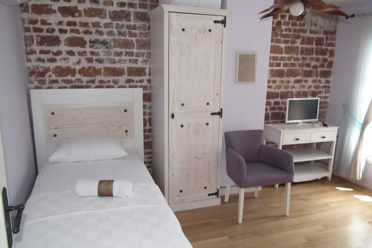 A bedroom with a wooden bed, a wardrobe, a desk with a computer, and a chair.