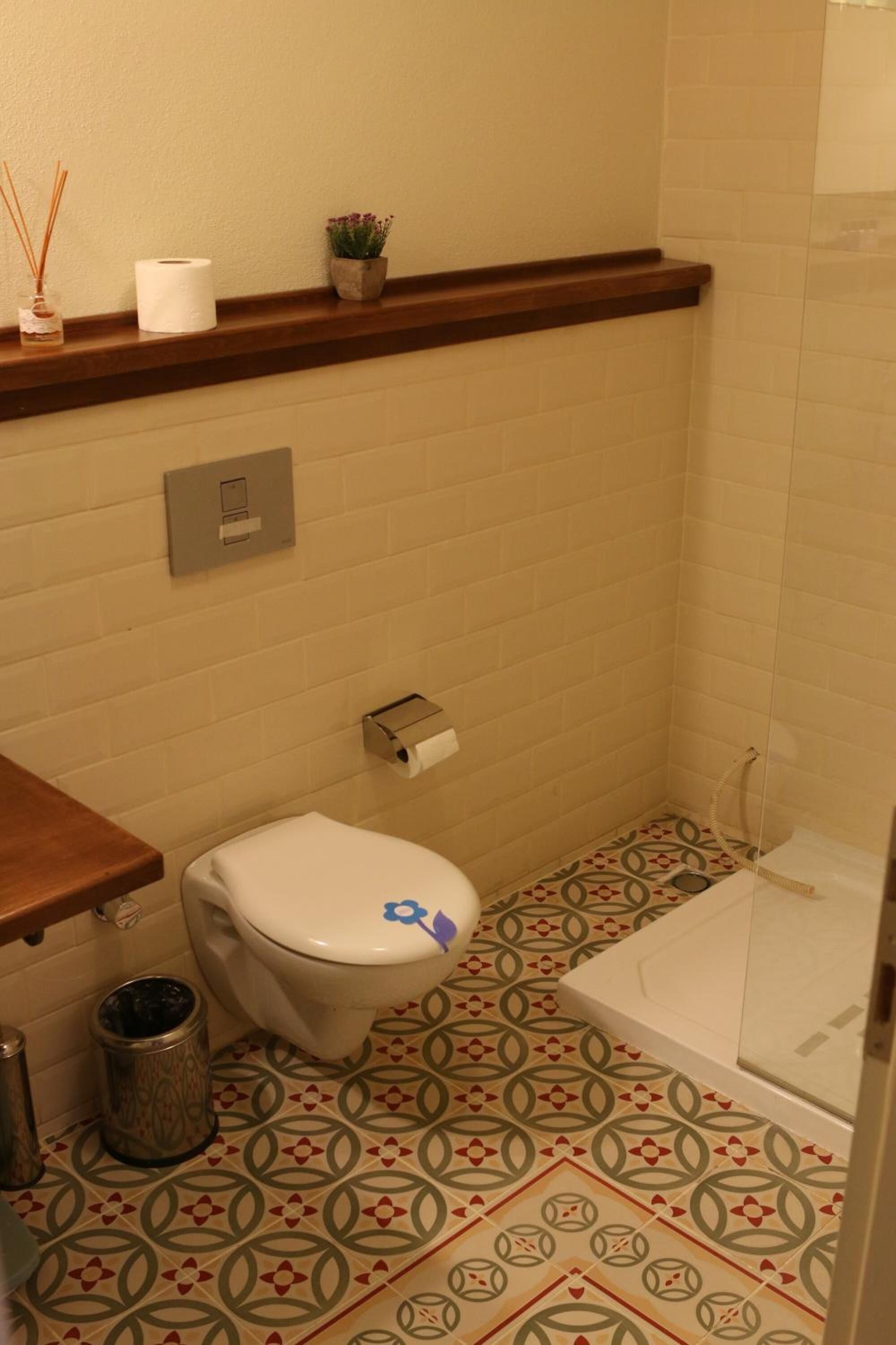 A small bathroom with a toilet, a trash can, and a shower.