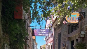 Una estrecha calle adoquinada flanqueada por edificios, algunos con carteles que indican negocios locales.