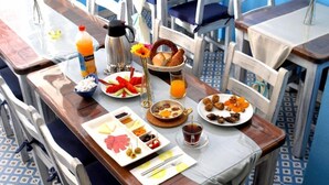 A breakfast setup with various dishes, a coffee pot, and a juice bottle on a wooden table. - Gizemli Konak (Ayvalik)