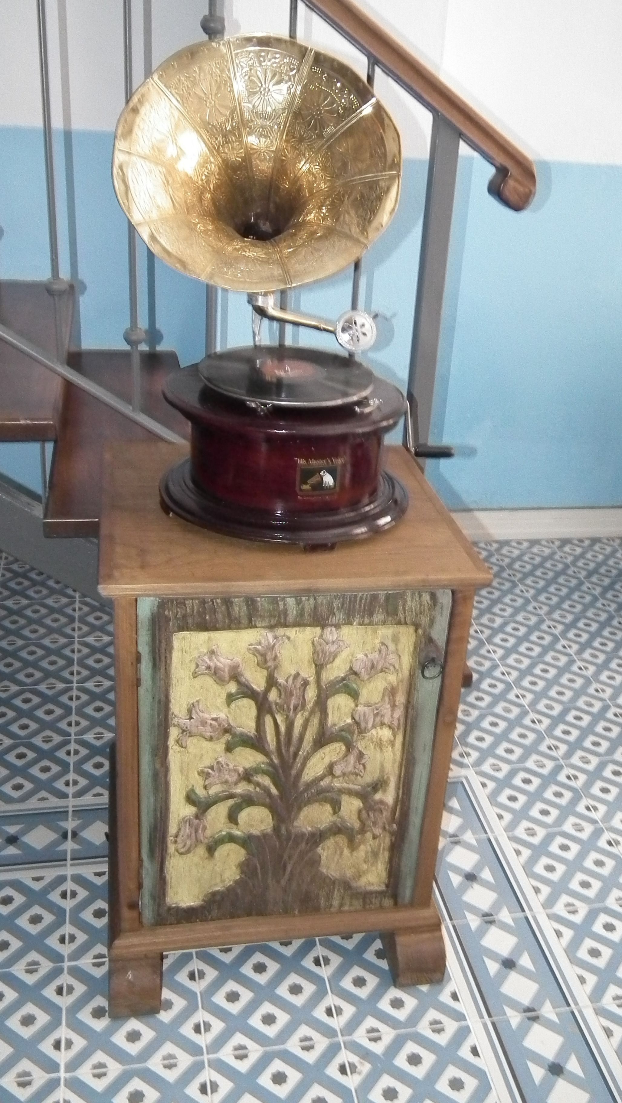 Ein Grammophon im Vintage-Stil auf einer Holzkassette mit floralem Dekor.