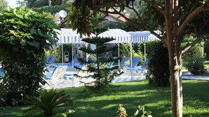 A pool area with lounge chairs and striped umbrellas. - Hulusi Hotel (Manavgat)