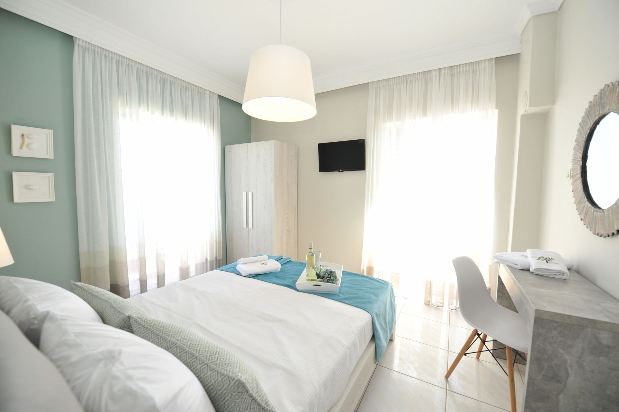 Ein Hotelzimmer mit zwei Betten, einem Schreibtisch, einem Stuhl, einem Fernseher und einem Spiegel.