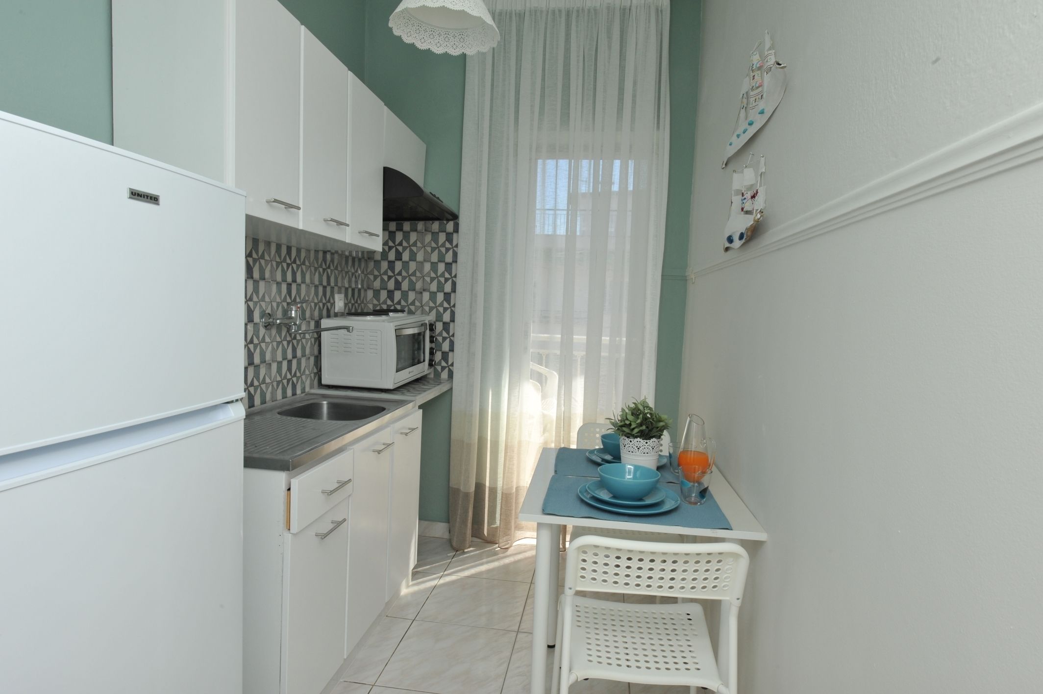 A compact kitchen with white cabinets, a microwave, and a dining area with a table and chairs.