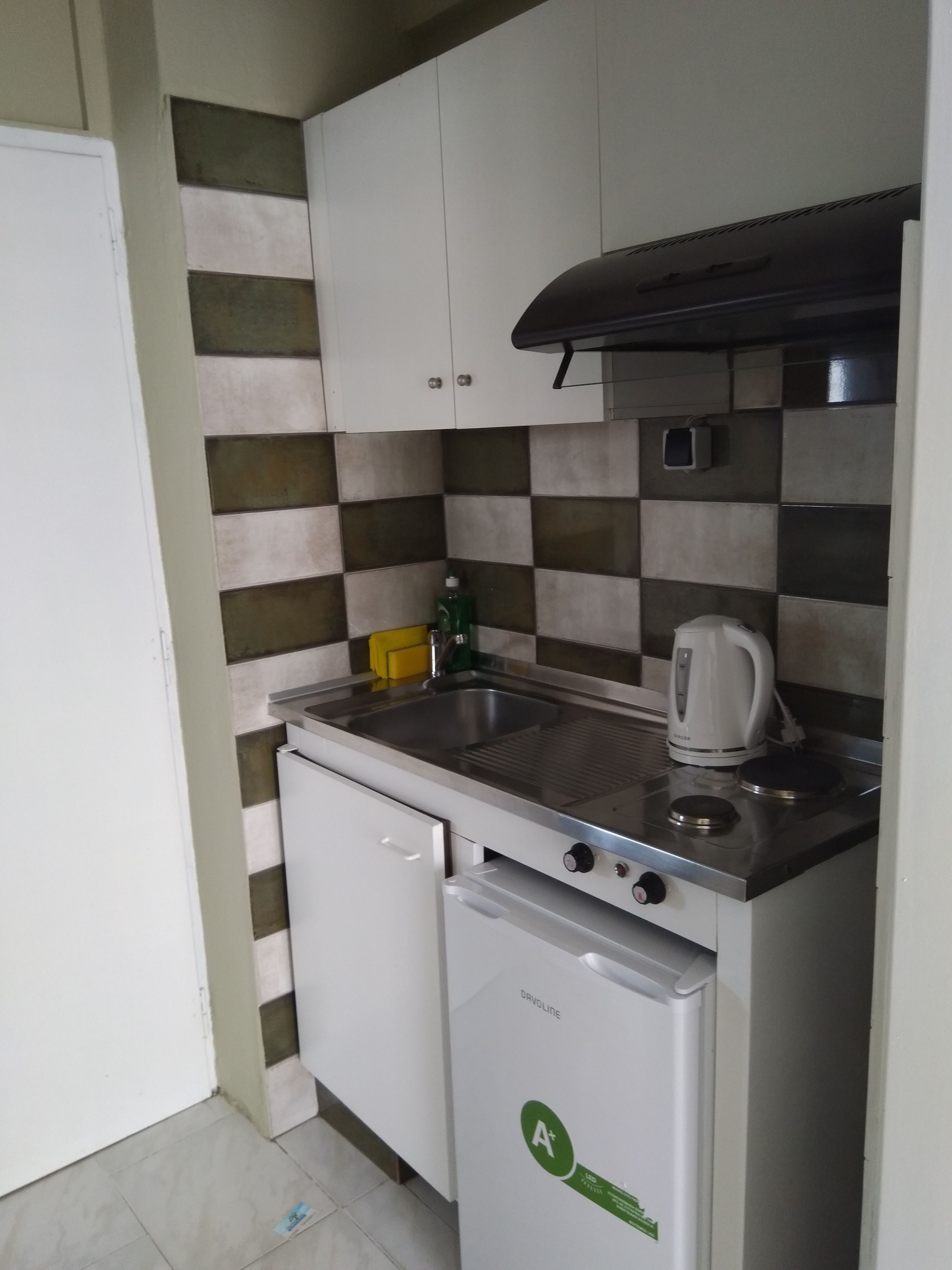 A compact kitchen with a sink, a kettle, and a dishwasher.