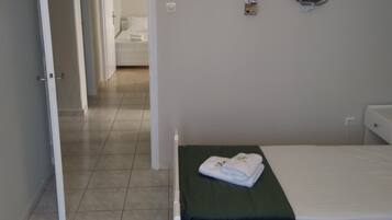 A hotel room with two beds, a bathroom, and a hallway leading to another room.