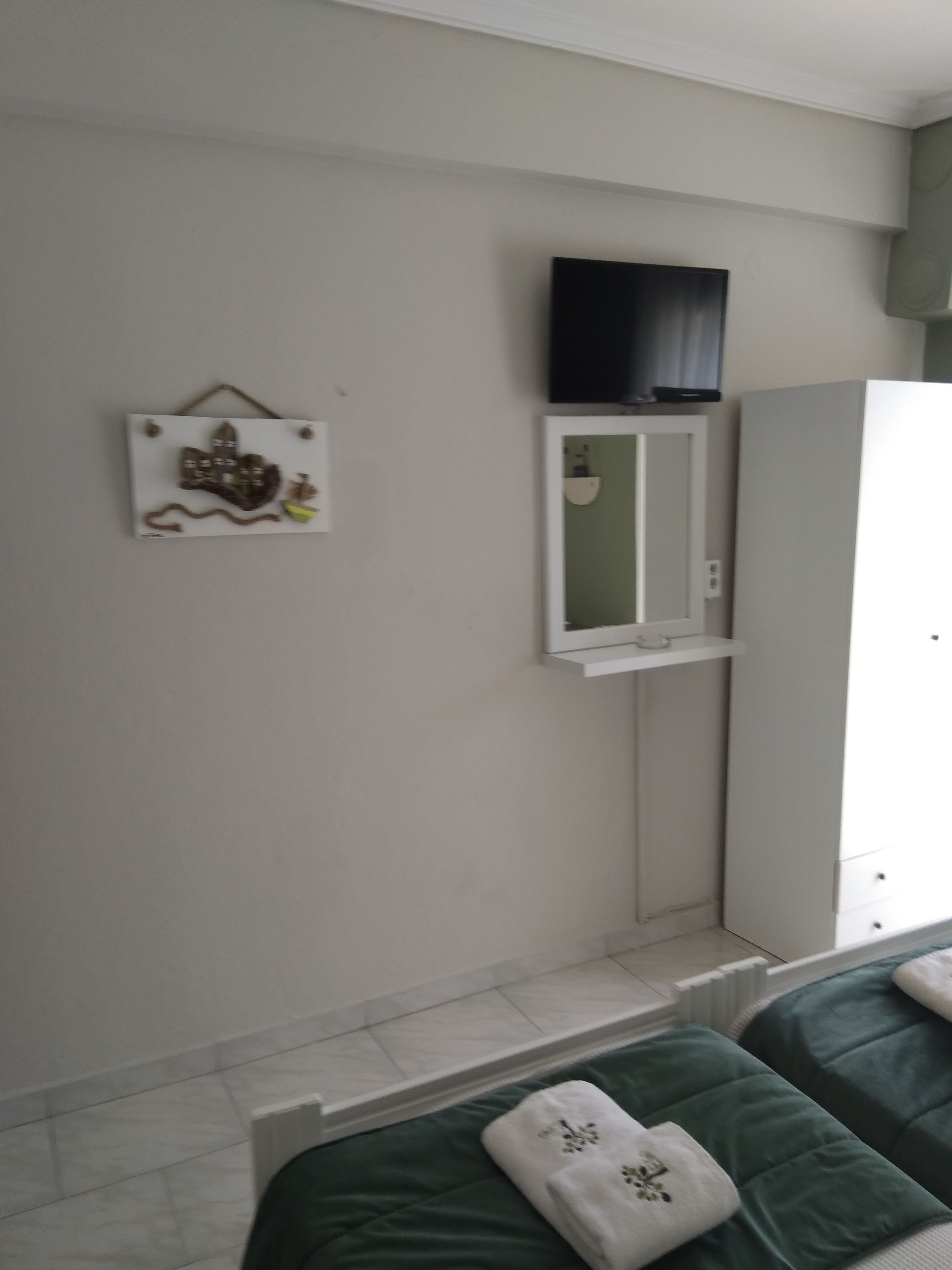 Un dormitorio con cama, televisor montado en la pared, espejo y armario.