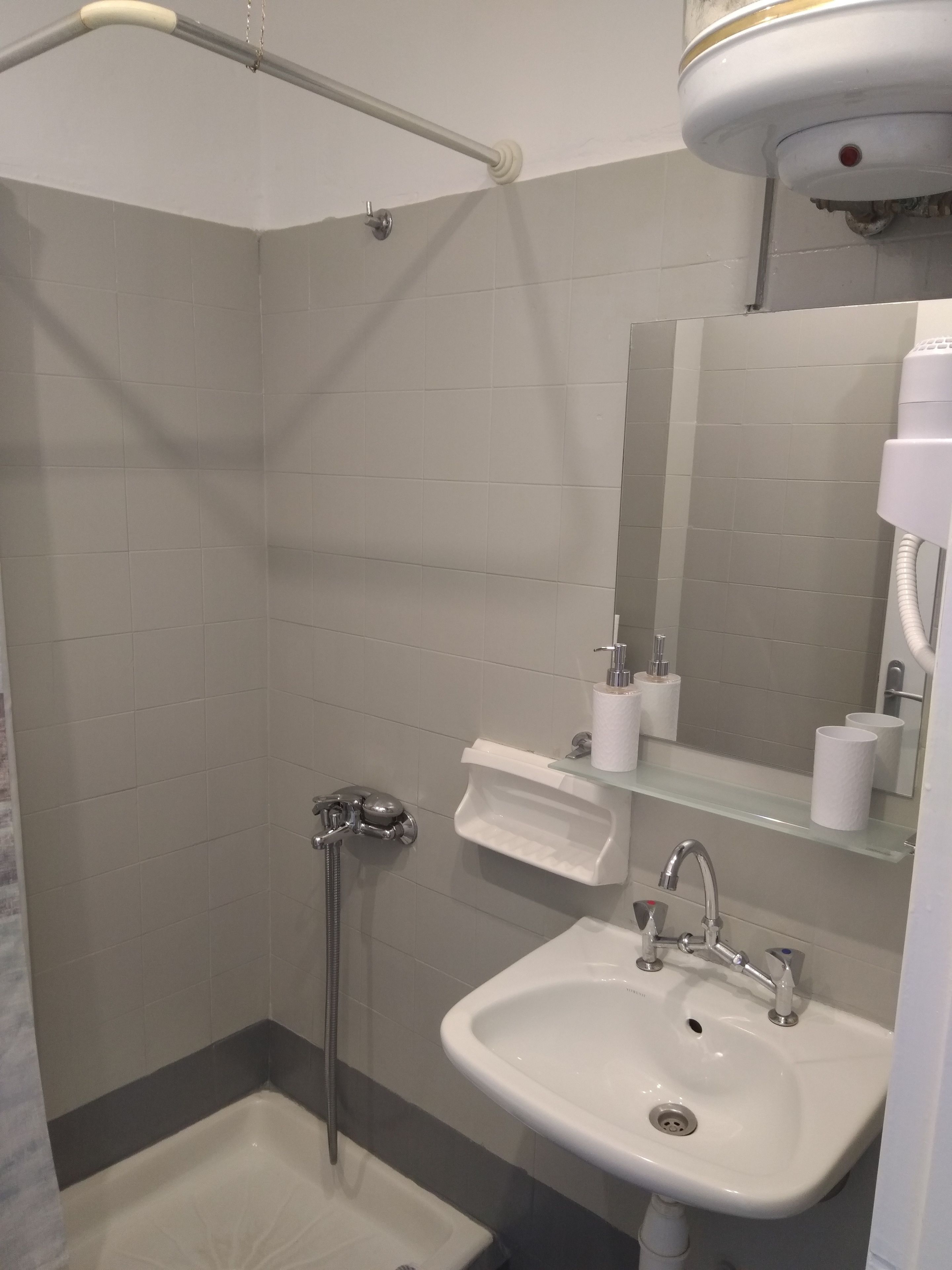 A bathroom with a shower, a sink, and a mirror.