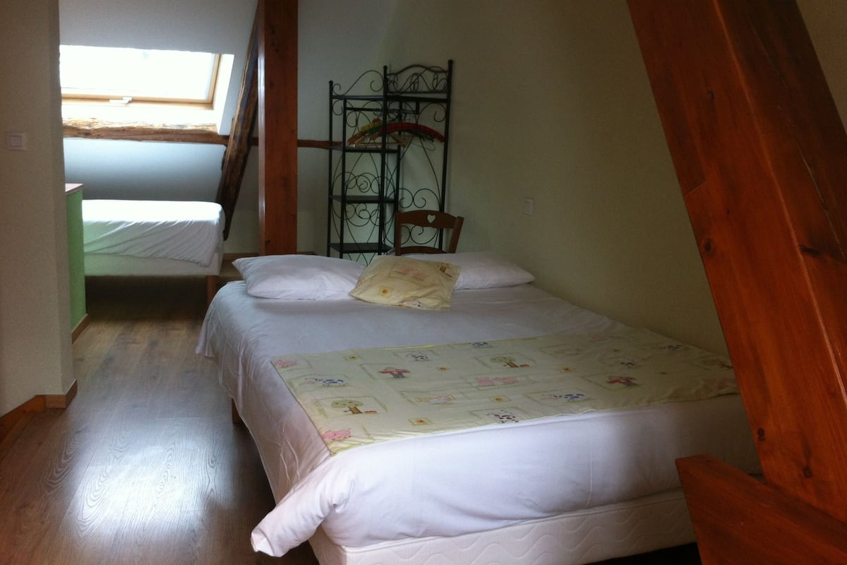 Ein Zimmer mit zwei Betten, einem Holzstuhl und einem Metallregal.