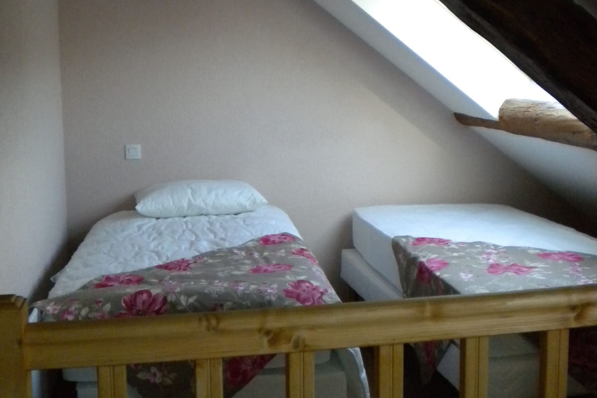Ein kleines Schlafzimmer im Mansardenstil mit zwei Betten, einer geneigten Decke und einem Dachfenster.