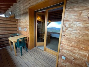 Une cabane en bois comprenant un coin repas, un escalier et une grande porte-fenêtre coulissante donnant sur un espace extérieur.