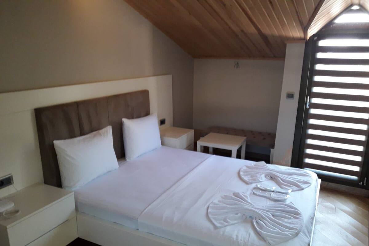 A bedroom with a bed, bedside tables, and a window with blinds.