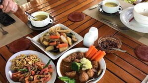 Una mesa de madera con varios platos, incluyendo una ensalada, un guiso de carne con verduras y una sopa.