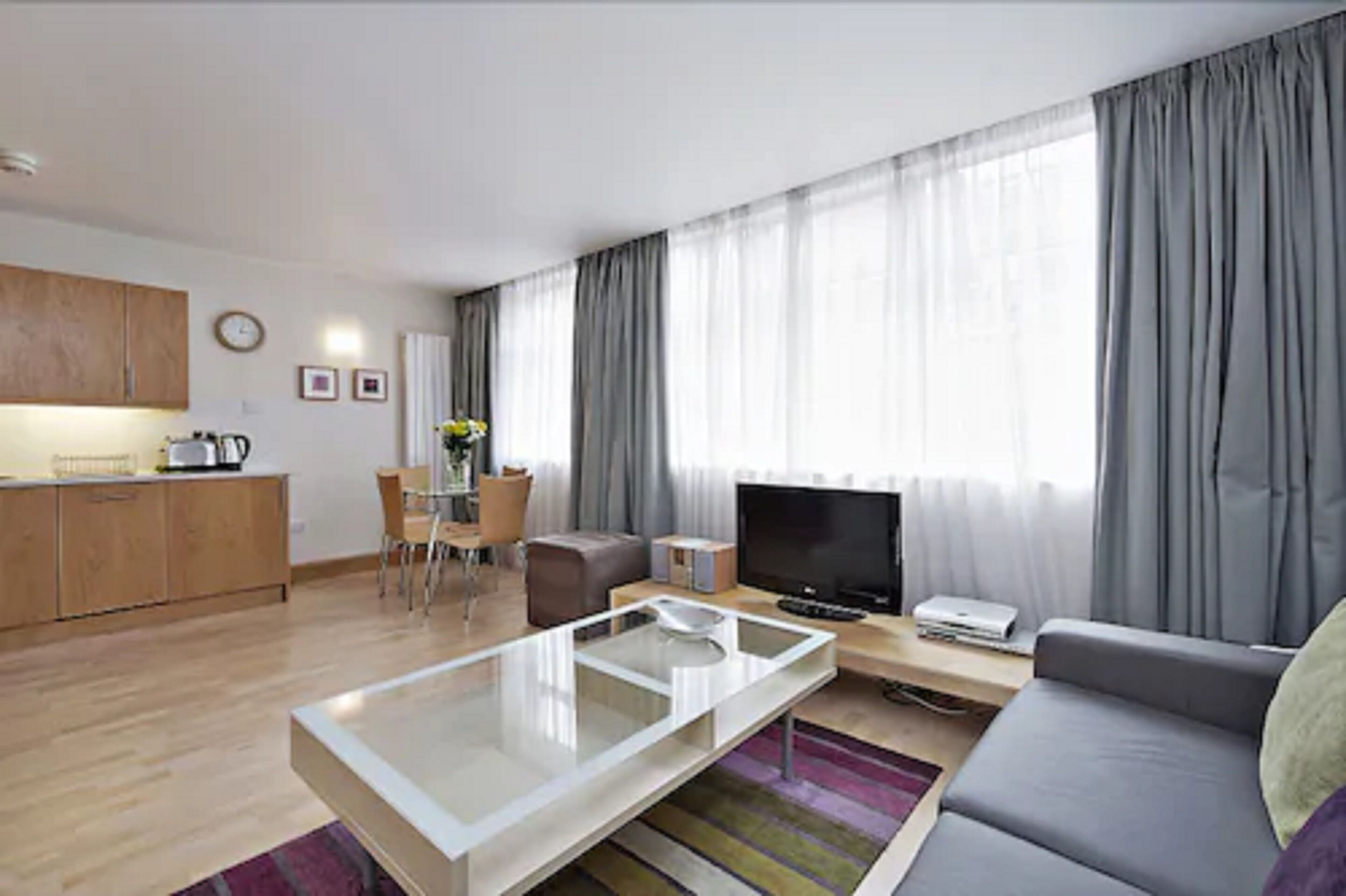 Ein modernes Wohnzimmer mit Sofa, Couchtisch, Fernseher und Essbereich.