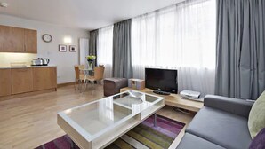 Ein modernes Wohnzimmer mit Sofa, Couchtisch, Fernseher und Essbereich.