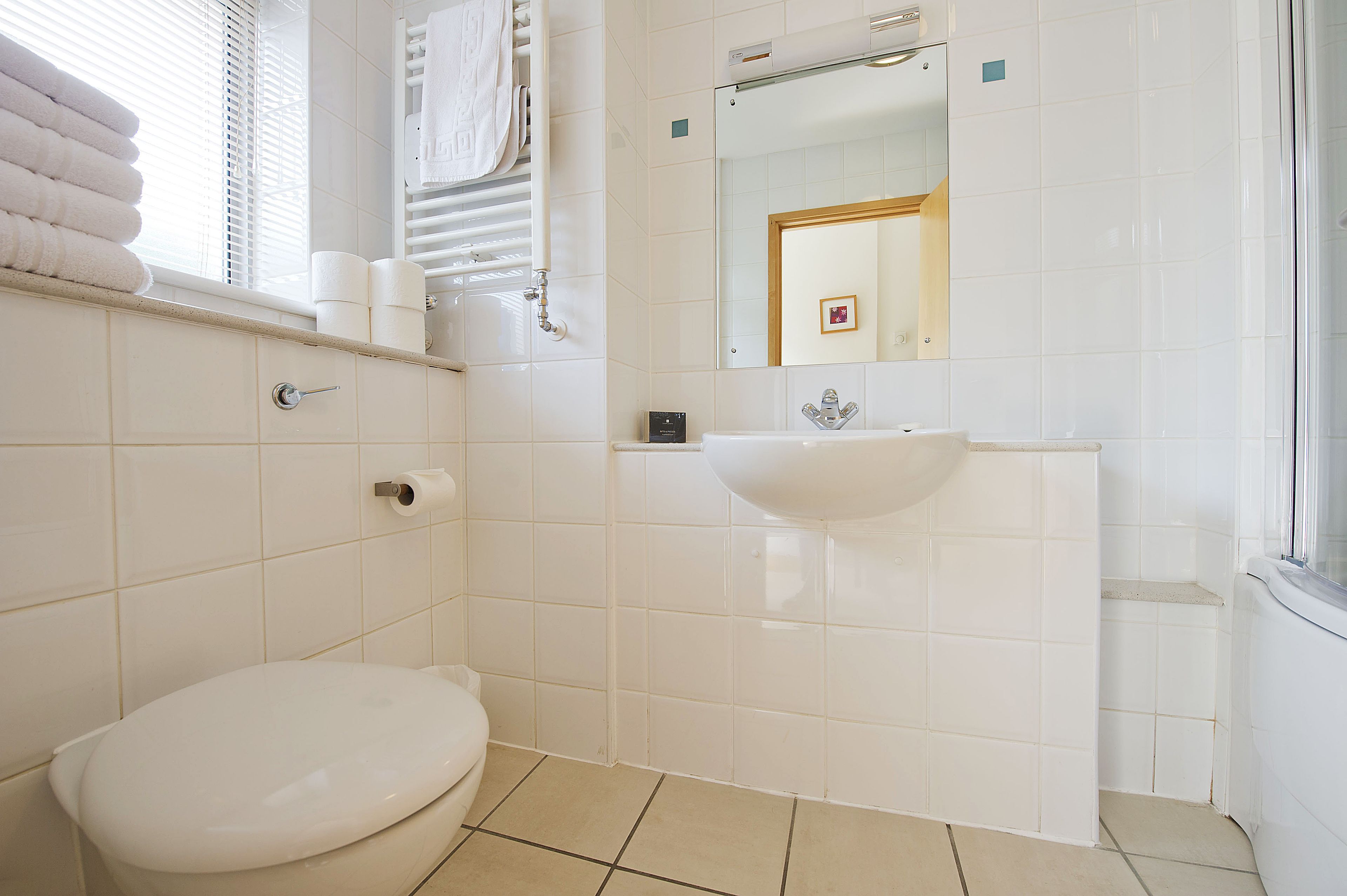 A bathroom with a toilet, sink, and towel rack.