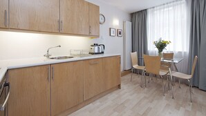 Eine moderne Küche mit Holzschränken, einer Spüle und einem Essbereich mit Tisch und Stühlen.