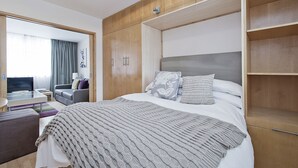 Ein modernes Hotelzimmer mit einem großen Bett, einem Schreibtisch mit Stuhl, einer Couch und einem Fernseher.