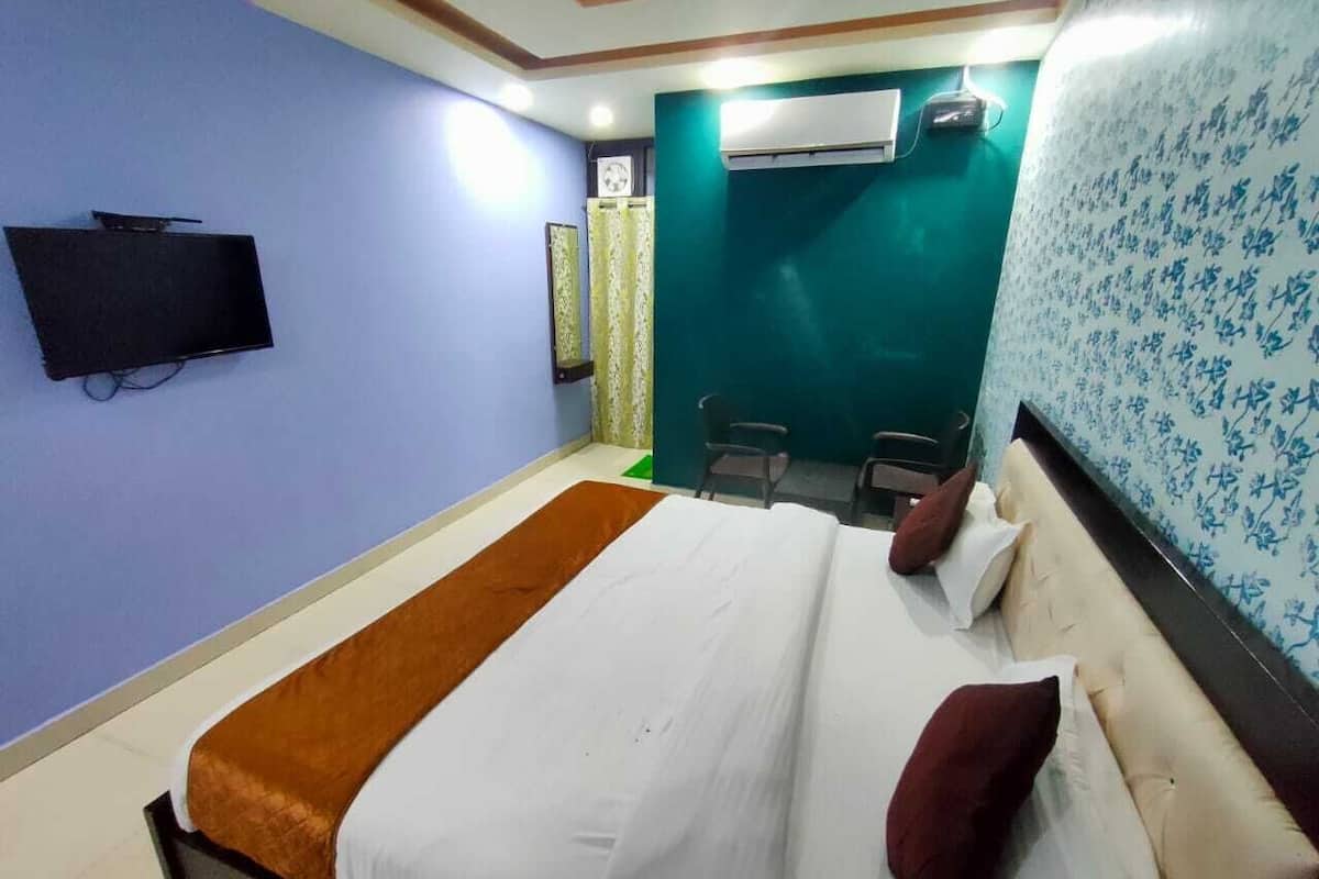 Quarto de hotel com cama, televisão, escrivaninha e cadeira.