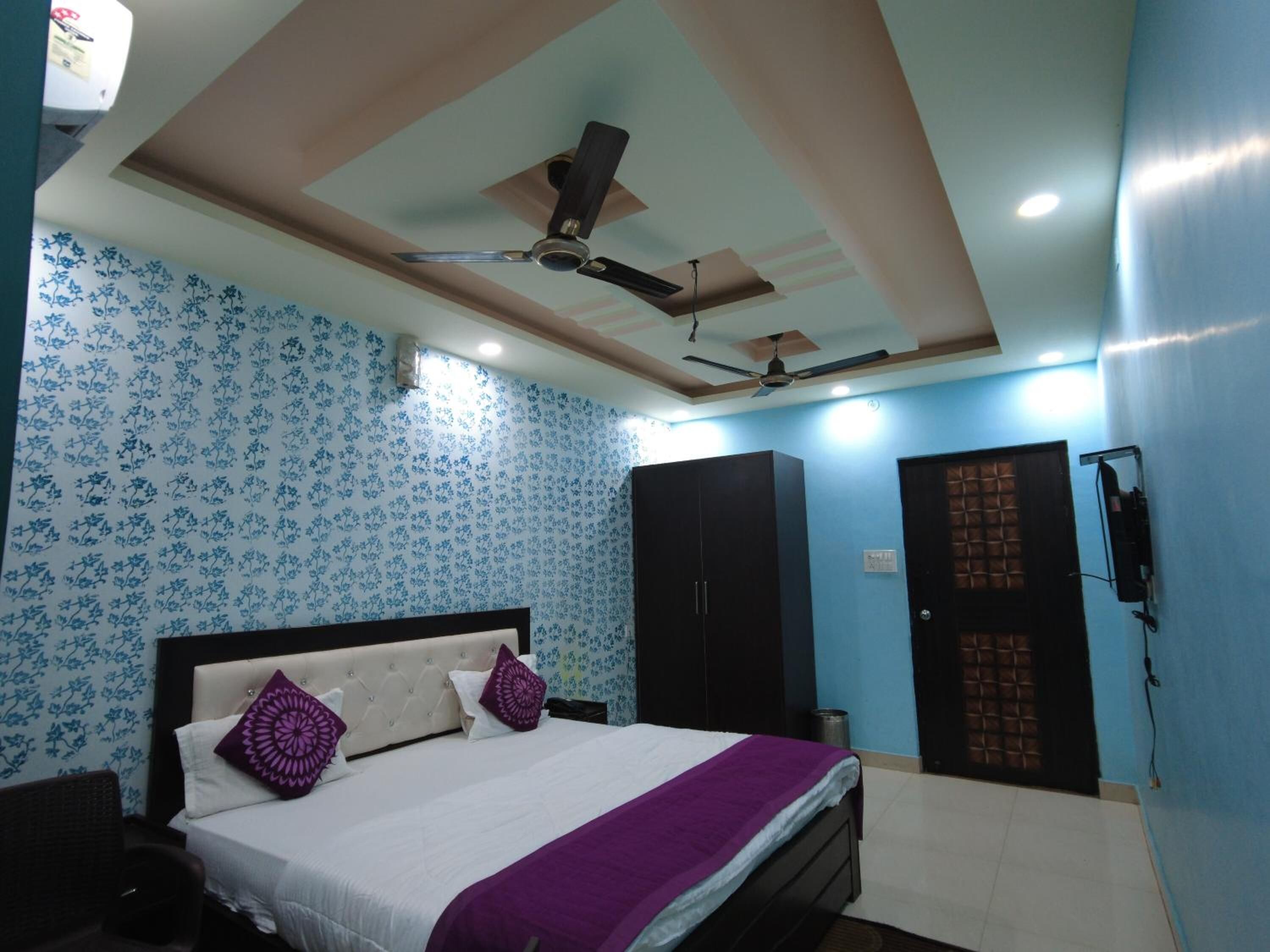 Un dormitorio con cama, dos ventiladores de techo, un armario y una puerta con ventanal.