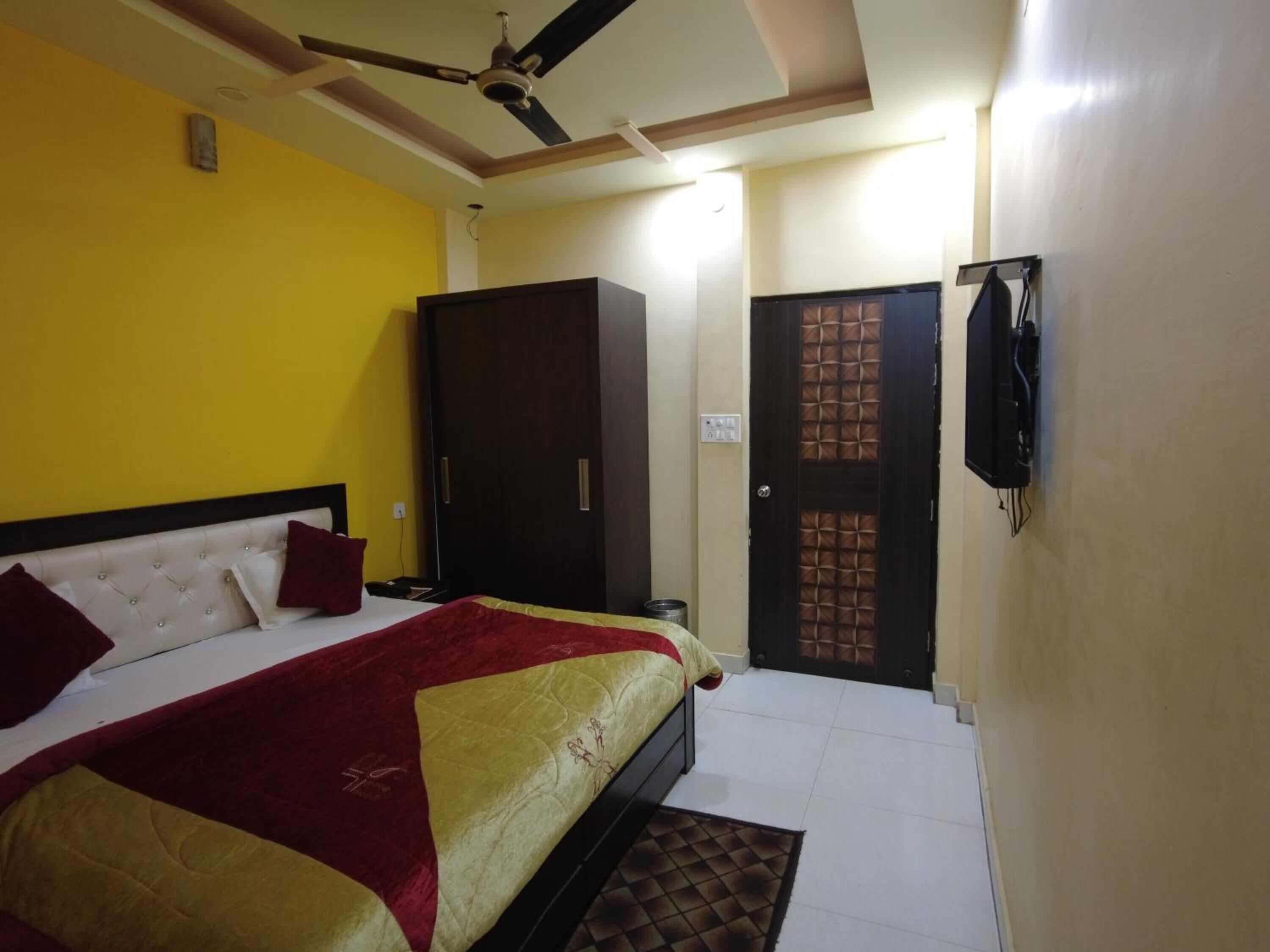 A bedroom with a bed, wardrobe, and a television mounted on the wall.