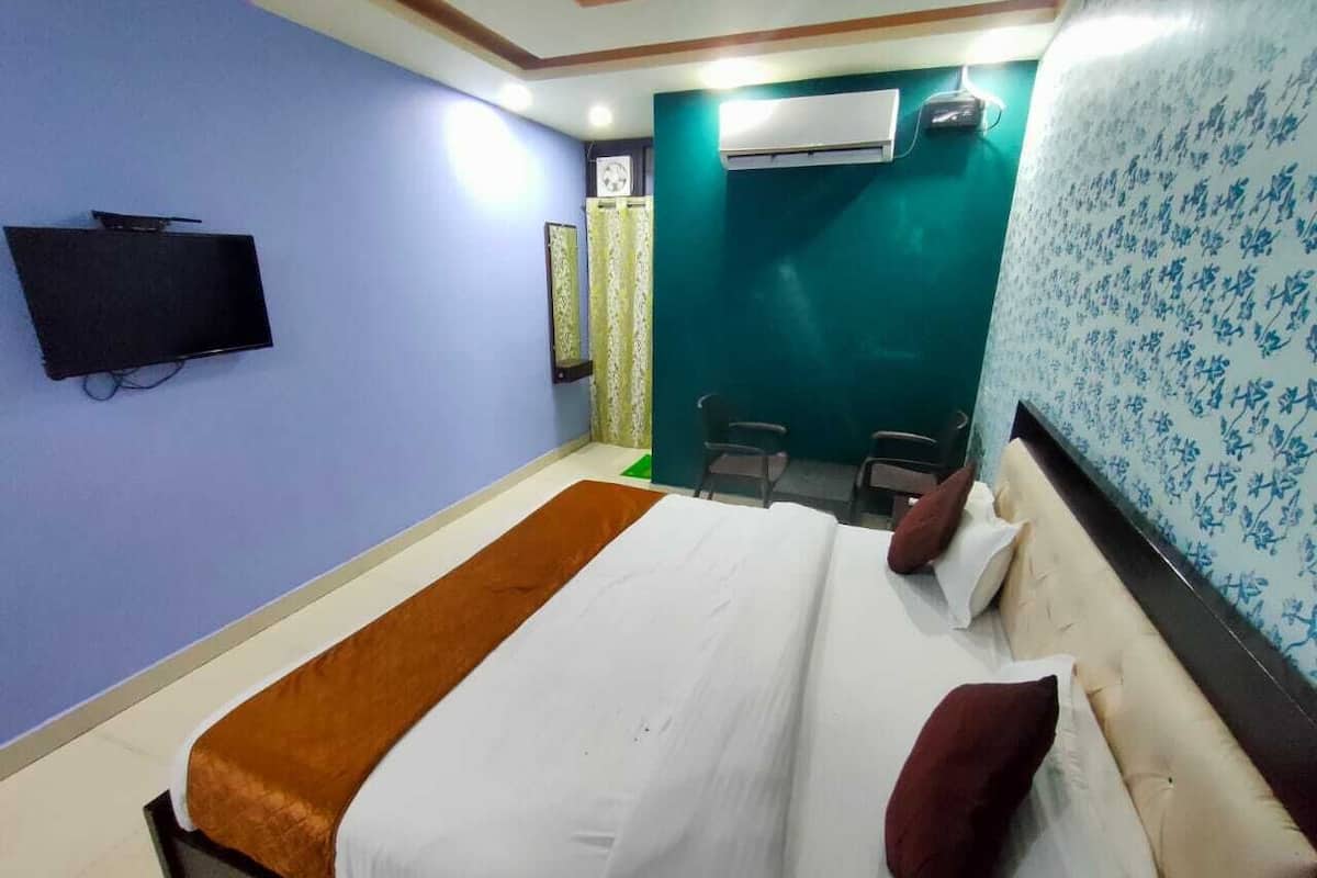 Quarto de hotel com cama, televisão, escrivaninha e cadeira.