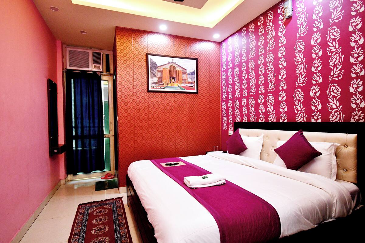 Quarto de hotel com uma cama, um quadro na parede e uma janela com cortinas.