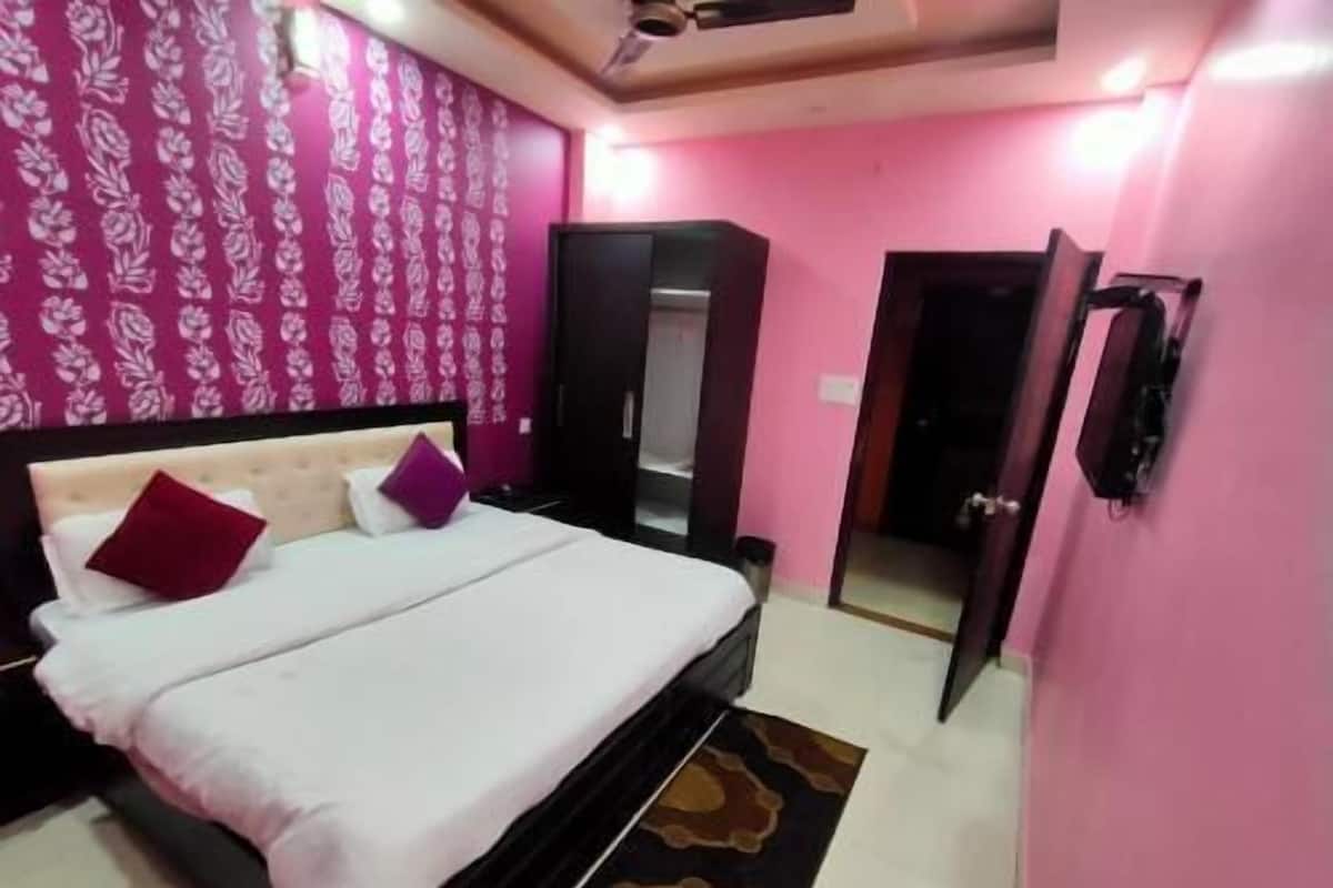 Quarto com cama, guarda-roupa, espelho e televisão.
