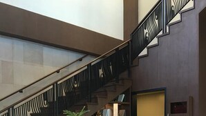 A reception desk with a modern design, a staircase with decorative railings, and a potted plant. - Bella Lifestyle Studio (Tagaytay)