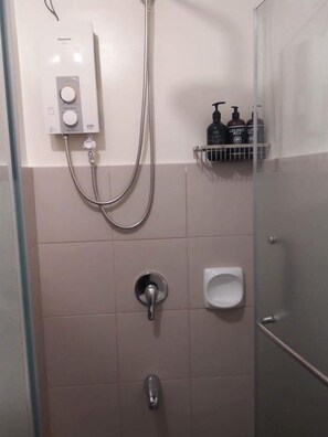 A bathroom with a shower, a toilet, and a soap dispenser. - Bella Lifestyle Studio (Tagaytay)
