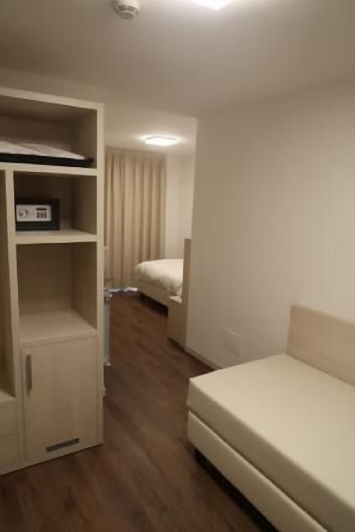A room with a bed, a wardrobe, and a desk.