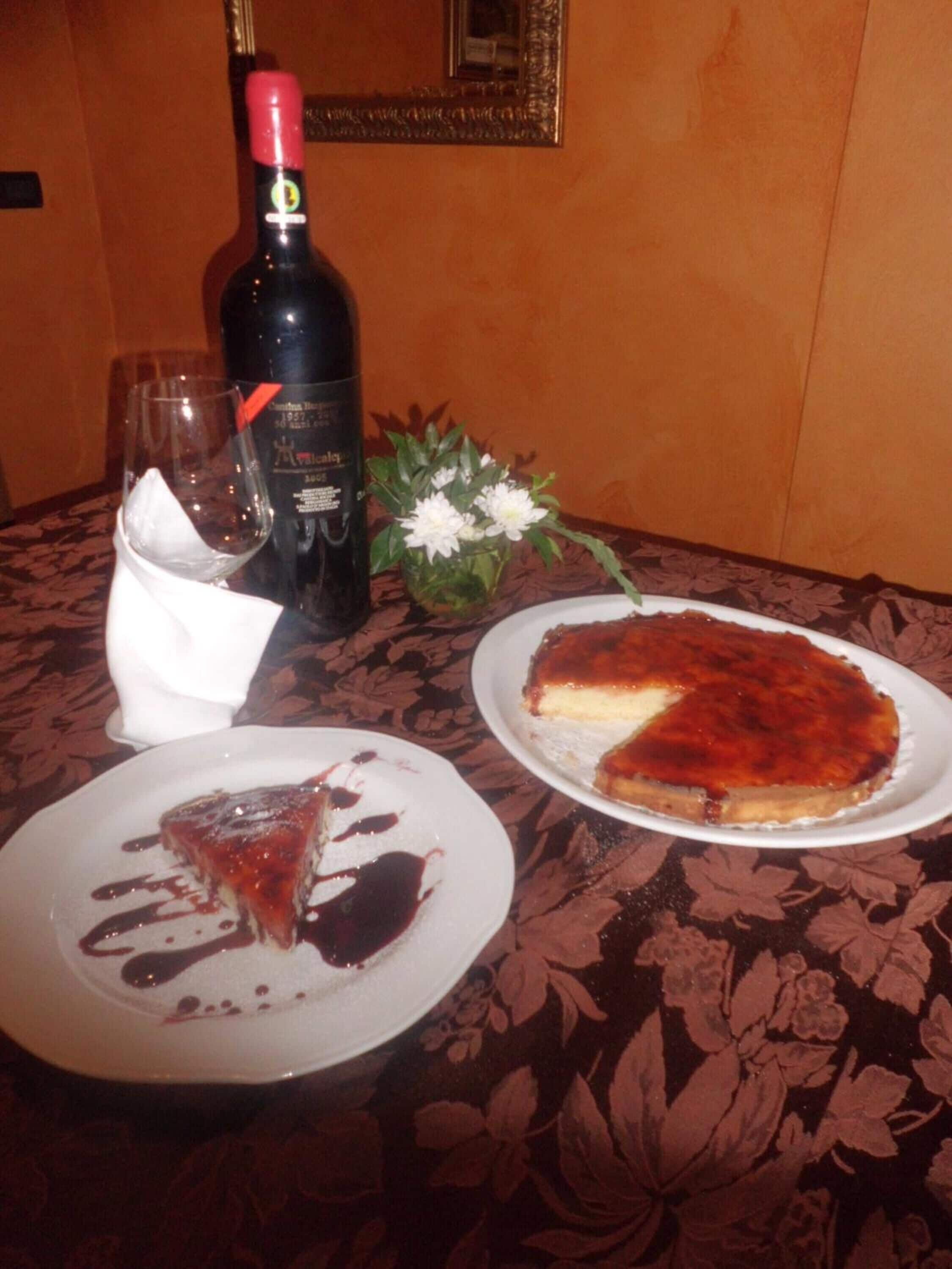 A dining table with a bottle of wine, a glass, and two plates of food.