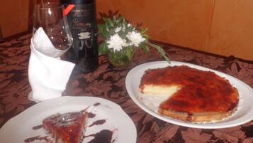 A dining table with a bottle of wine, a glass, and two plates of food.