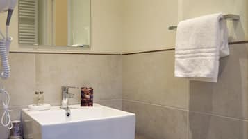 Une salle de bain moderne avec un lavabo blanc, un sèche-cheveux et un porte-serviettes.