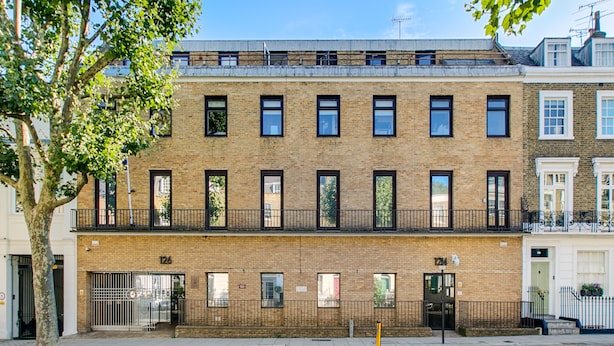 A multi-story brick building with a flat roof, numbered 126, featuring a balcony on the second floor and a gated entrance. - Camden Serviced Apartments by Globe (London)