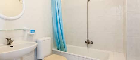 Et badeværelse med toilet, vask, badekar og bruser.