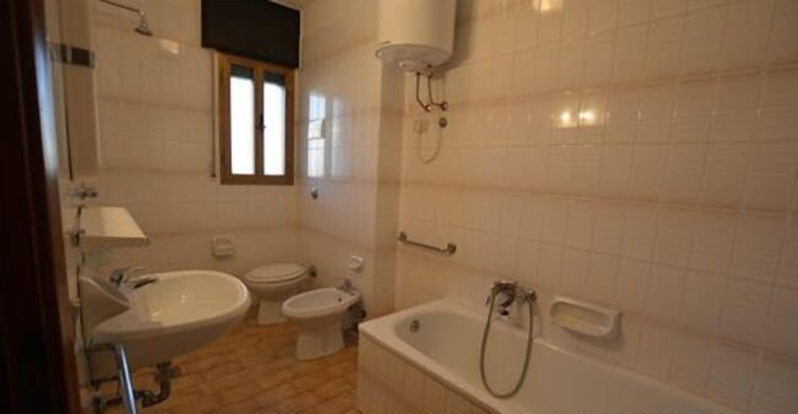 Un baño con una bañera, dos inodoros y un lavabo.