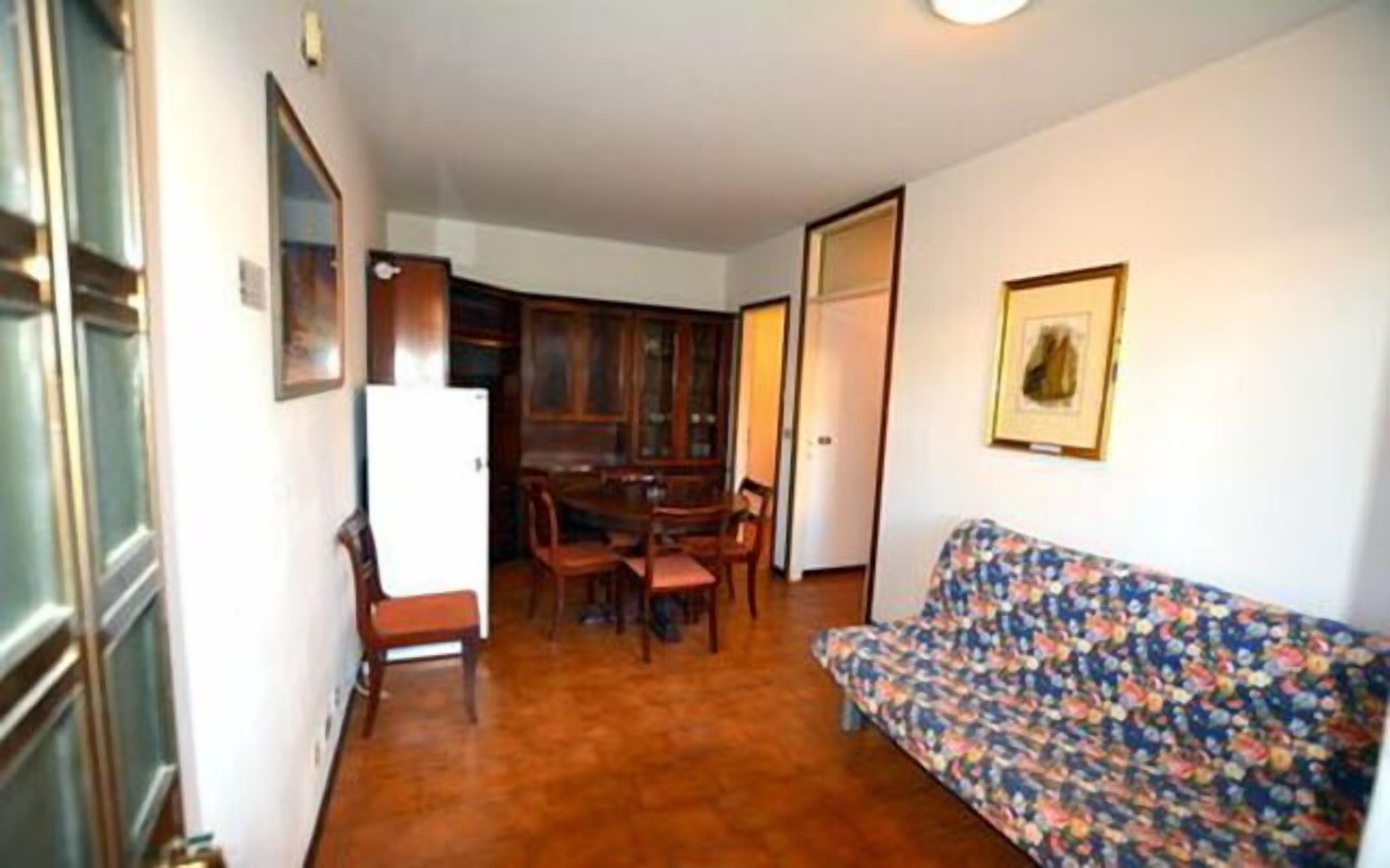A compact living space with a dining area, a sofa, and a refrigerator.