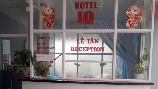A hotel reception area with a reception desk, a sign indicating 'HOTEL IQ' and 'LÊ TÂN RECEPTION'. - IQ Hotel (Ho Chi Minh City)