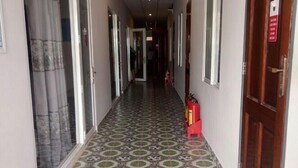 A hallway with patterned floor tiles, doors on both sides, and a fire extinguisher on the right. - IQ Hotel (Ho Chi Minh City)